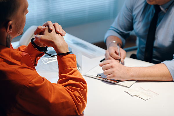 Criminal in Handcuffs Talking to Detective filling witness statement forms